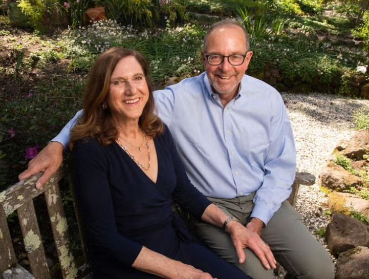 A photo of Renee and Mike Child sitting on a bench in a vibrant garden. 