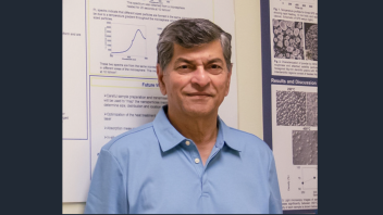A headshot of Dr. Subhash, who is in front of a scientific poster. he is wearing a blue collar shirt. 