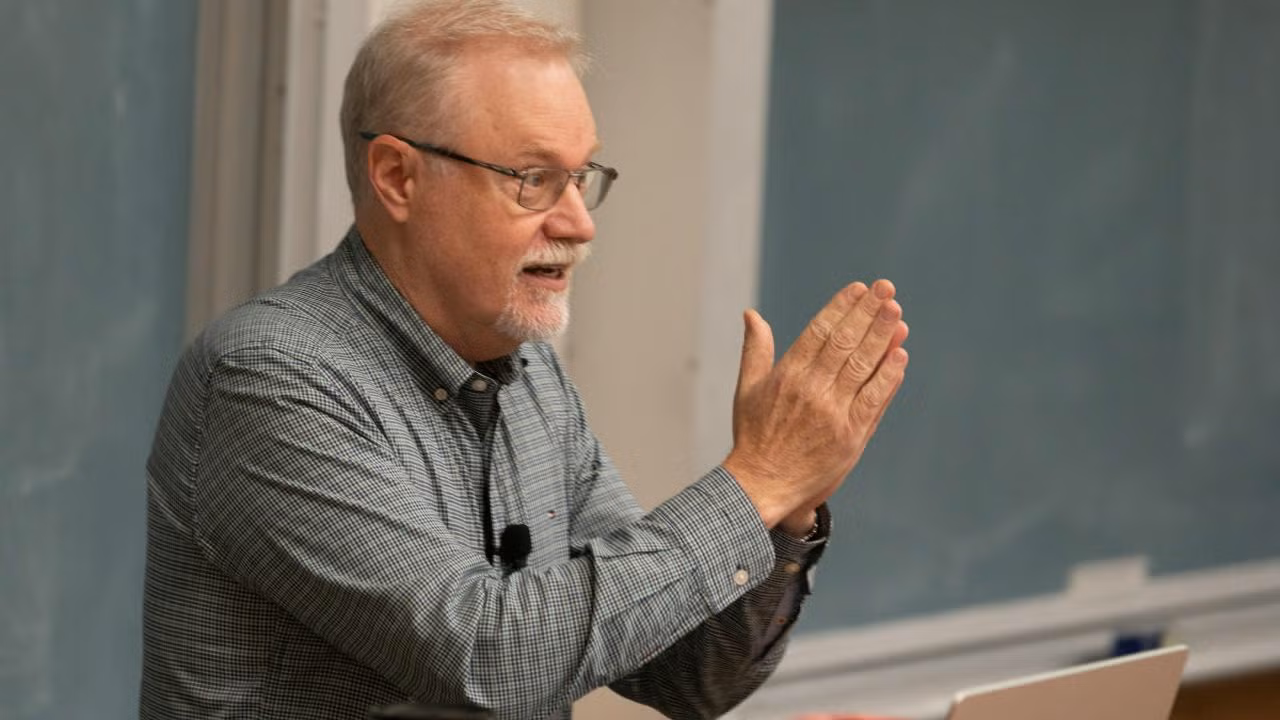 Professor Steve Luck teaching. This photo is a close up of his right side-profile and his hands are pressed together, finger tips aligned and facing up. 