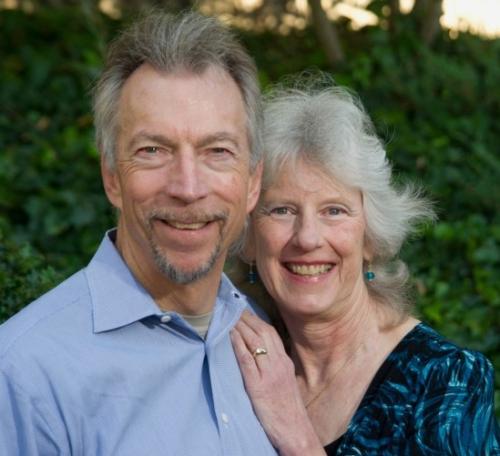 Karl Gerdes (on the left) and Pam Rohrich (on the right). Pam is learning on Karl, with her left hand on his chest. They are both smiling. 