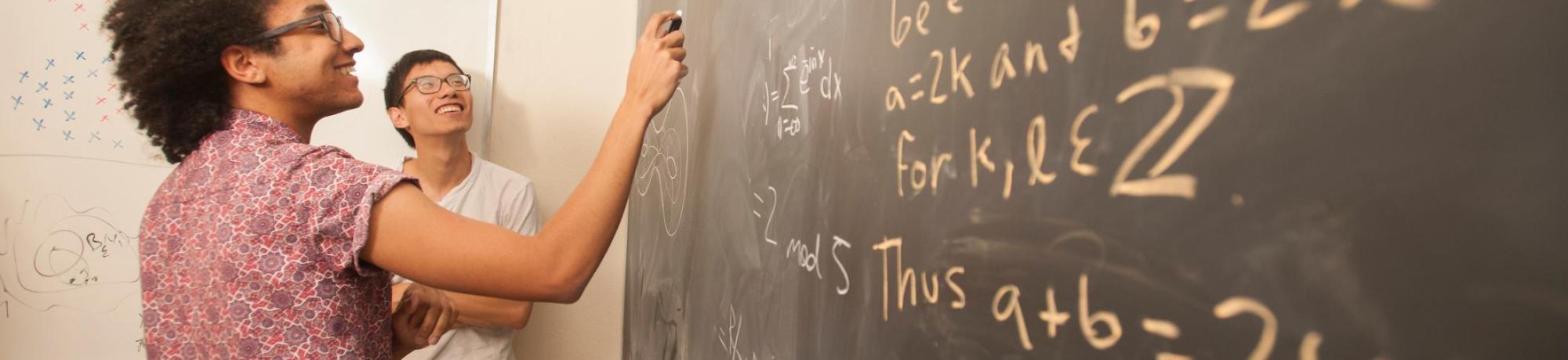 Students writing math equations on a chalkboard