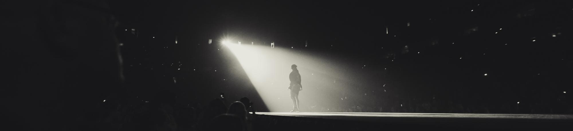  A black and white photo of someone being spotlighted on a stage